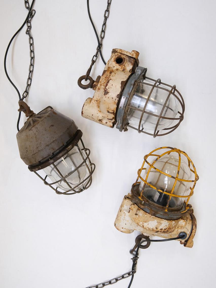 Tre rustikke industrielle lamper med metalkupler og kæder, lavet af genbrugsmaterialer og med tydelig patina, placeret på en hvid baggrund